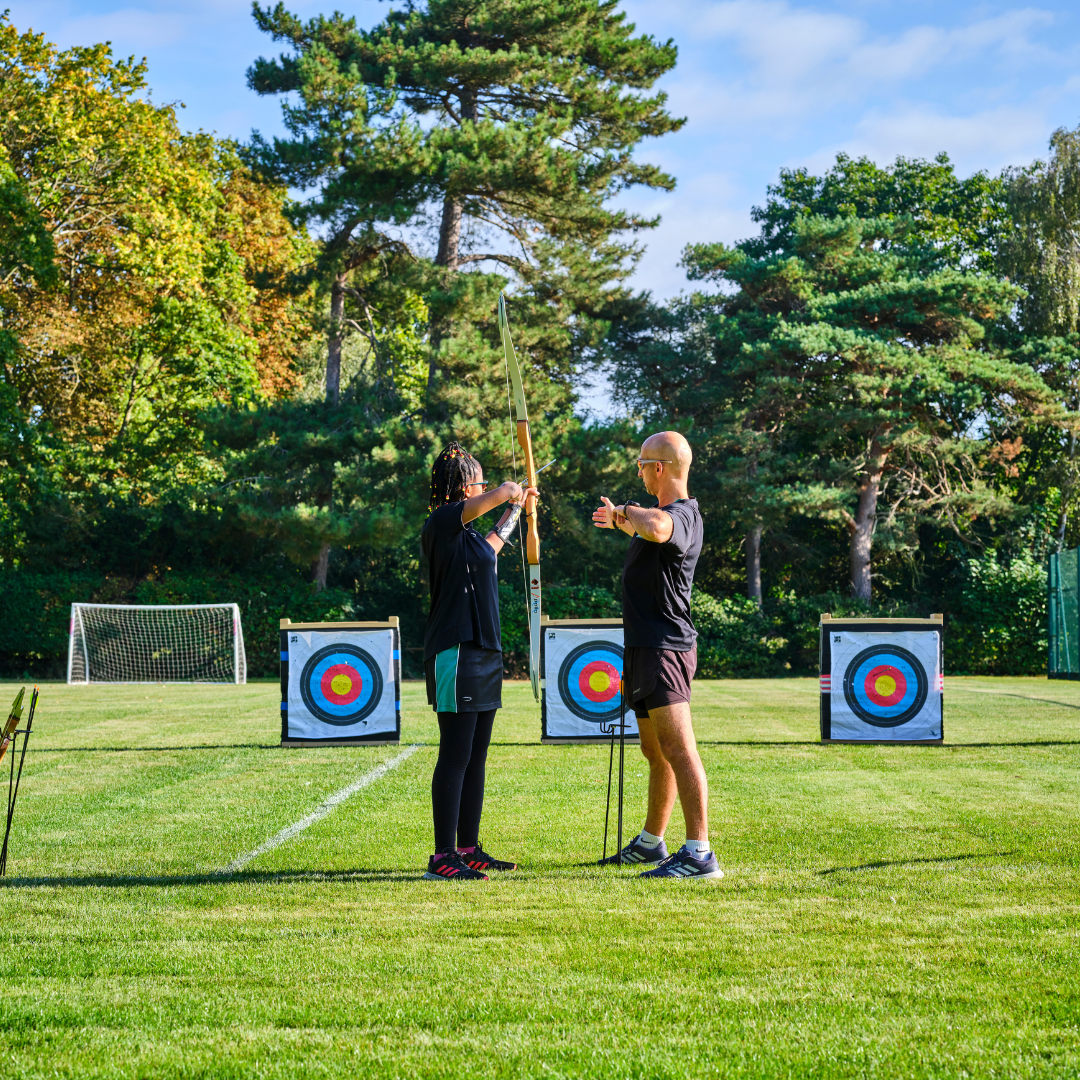 Front cover image of the 11-18 Co-curricular Programme Brochure showing a teacher and student undertaking archery