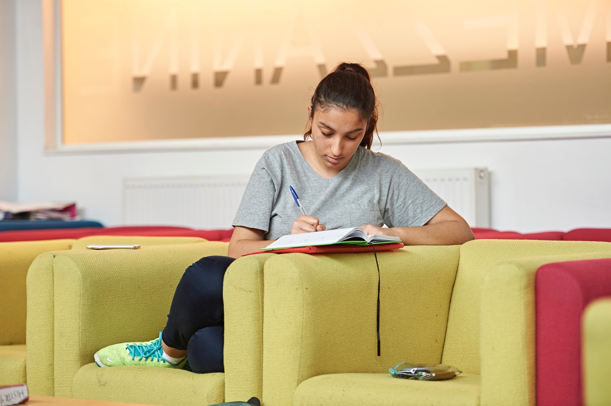 Student writing on a sofa